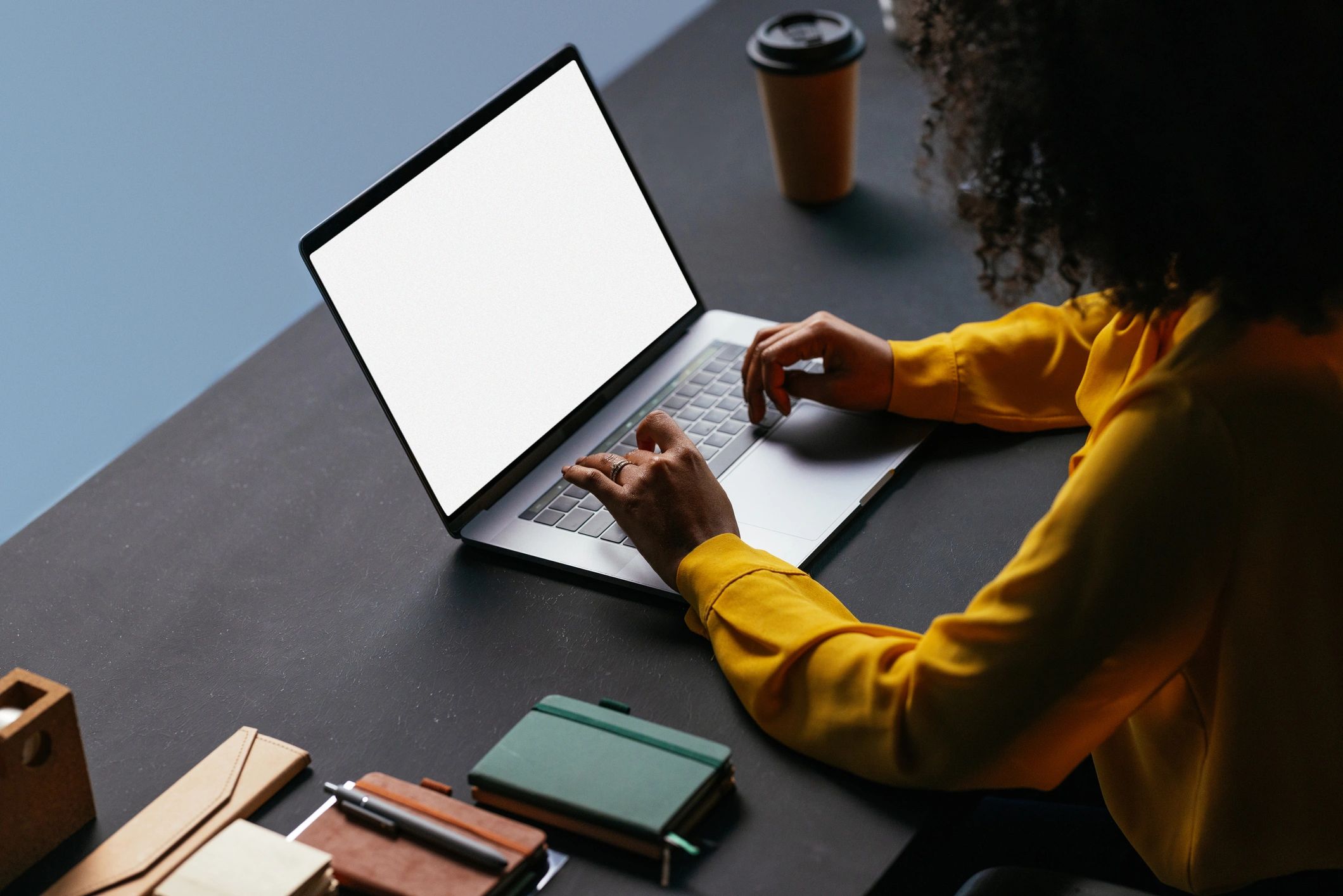 Student working at a desk with a laptop and notebook